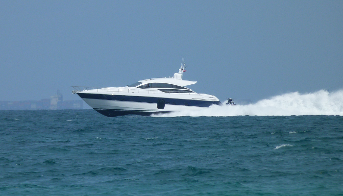 A powerboat speeds along blue water, leaving a white wake.