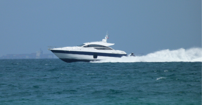 A powerboat speeds along blue water, leaving a white wake.